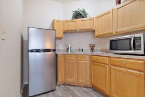 A modern kitchen with wooden cabinets, a stainless steel refrigerator, and a microwave on the countertop.