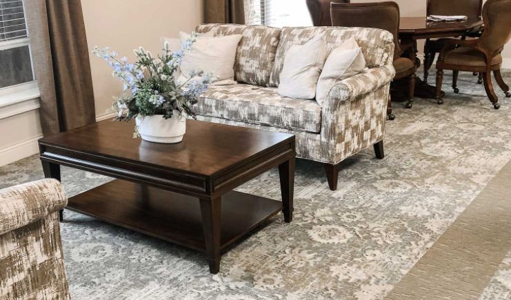 A cozy living room with a patterned sofa, dark wood coffee table, and floral rug.