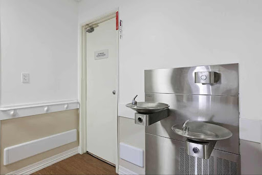 A minimalist interior featuring water fountains and a door.