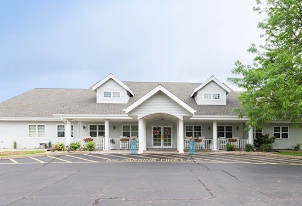 A large, white residential building with a symmetrical design and a welcoming front porch.