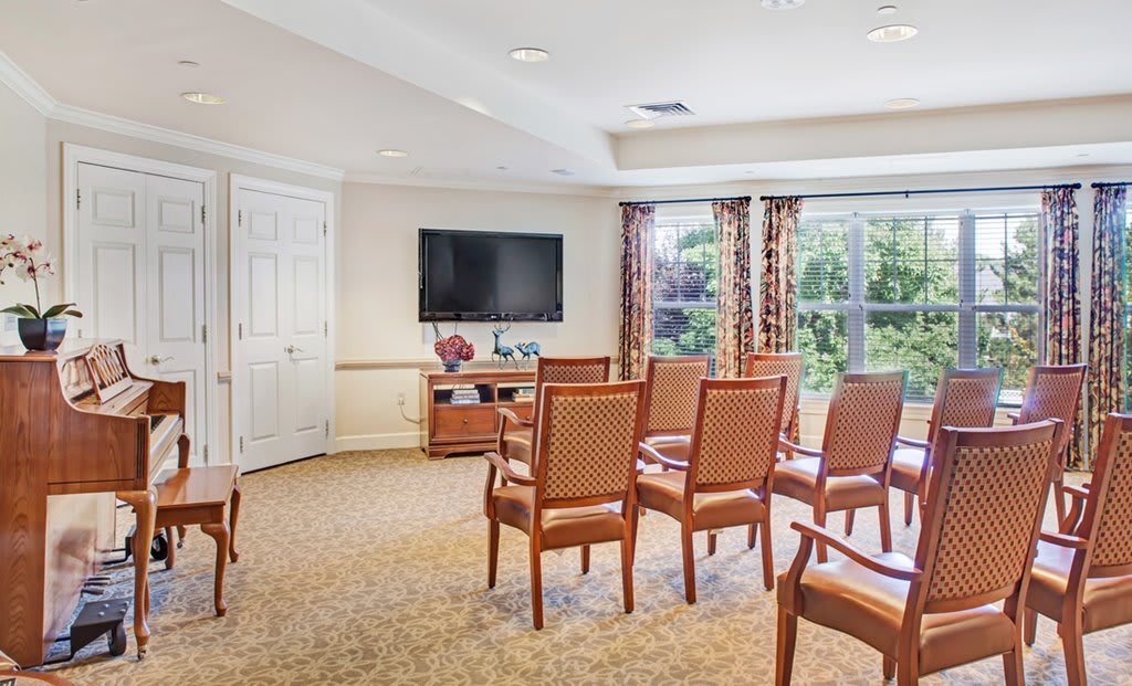 A well-lit conference room with arranged chairs facing a television.