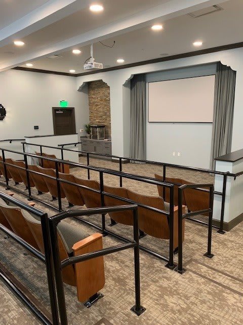 Small theater room with tiered seating and a projection screen.