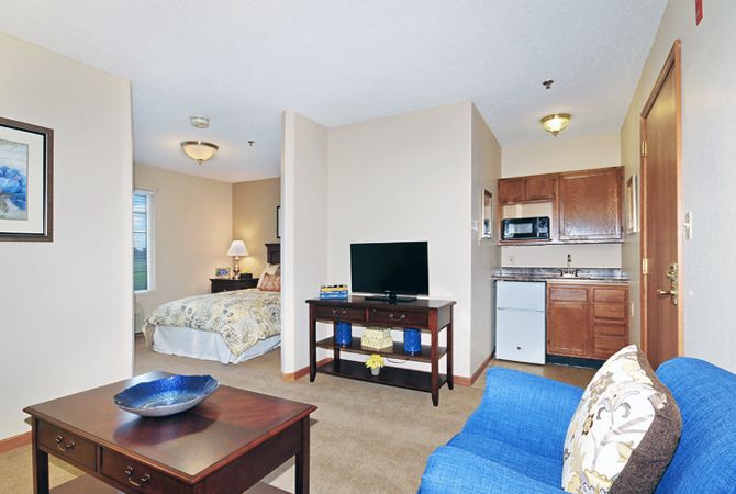A cozy apartment with an open layout featuring a living area, kitchenette, and adjoining bedroom.