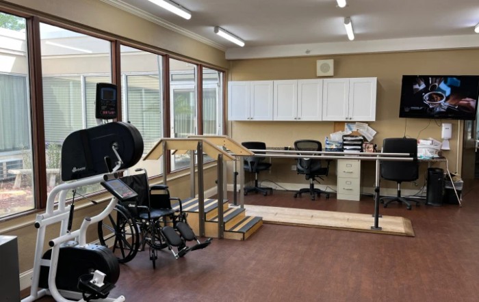 A rehabilitation room equipped with exercise equipment and a wheelchair, designed for physical therapy sessions.