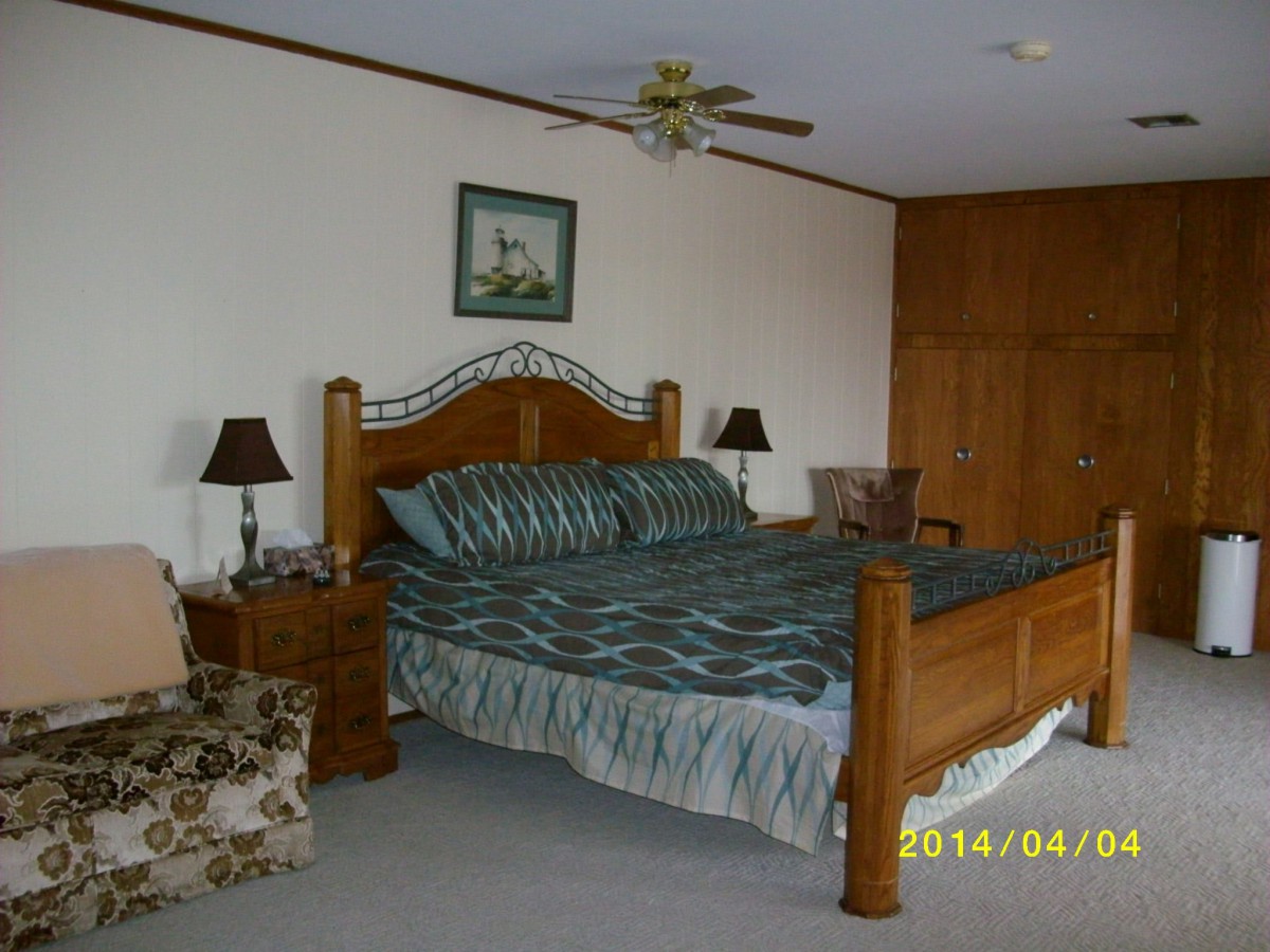 A cozy bedroom with a wooden bed frame and striped bedding, accompanied by nightstands and lamps.