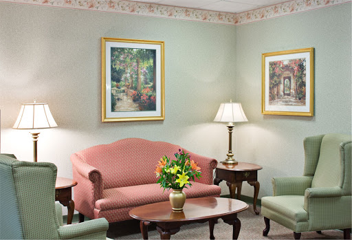 A cozy living room setup featuring a pink sofa, green chairs, and decorative art on the walls.