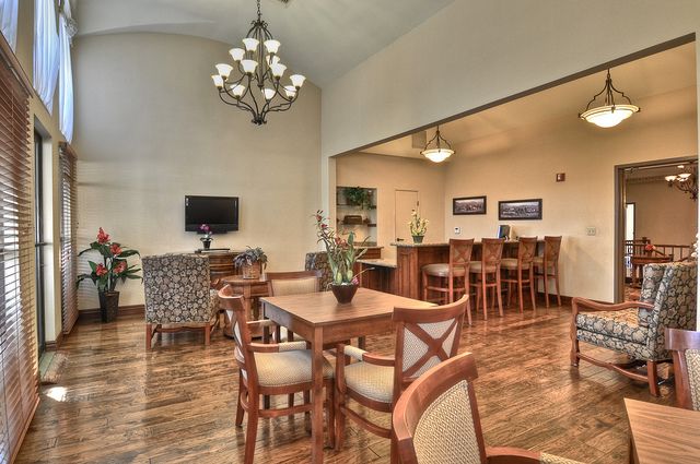 A cozy dining and lounge area featuring wooden furniture, a chandelier, and a bar with high chairs.