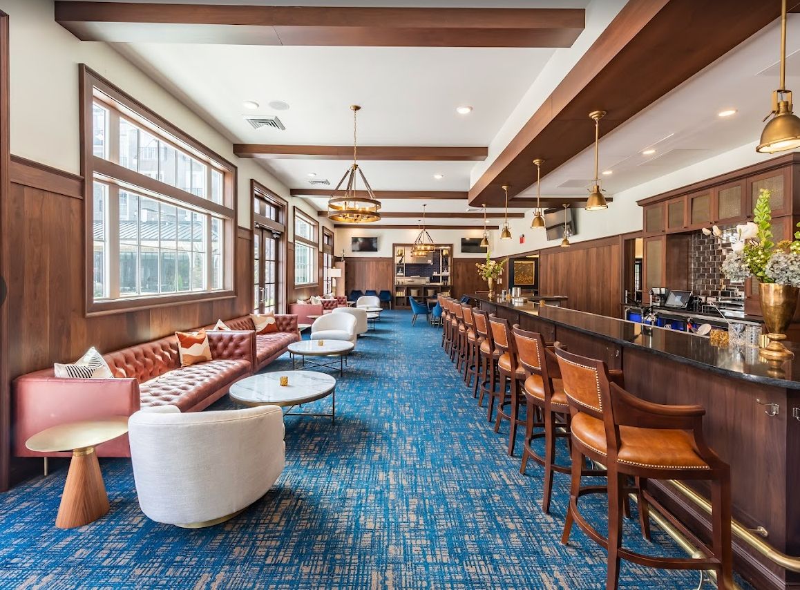 A modern lounge and bar area with comfortable seating, wooden accents, and large windows.