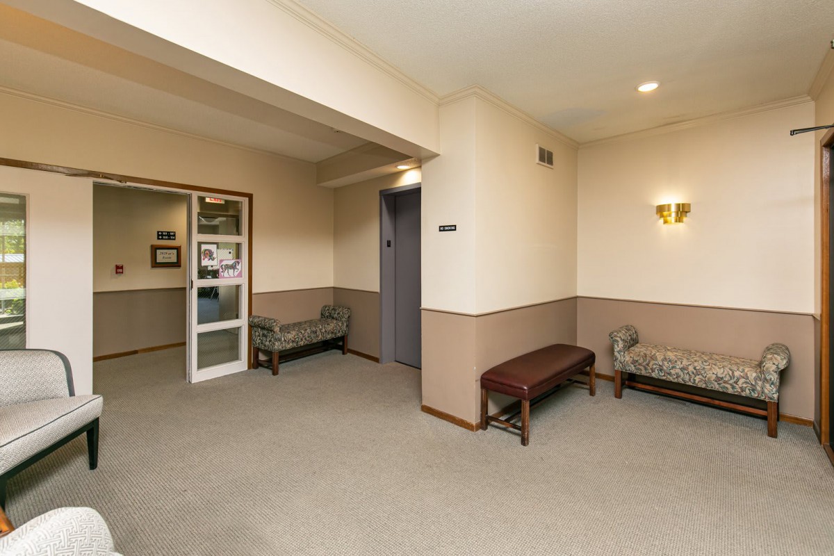 A quiet hallway with seating area featuring benches and a sofa, under soft lighting.