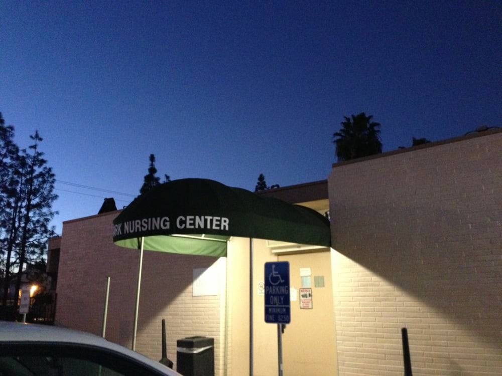 A building entrance with an awning and lights illuminated at night.