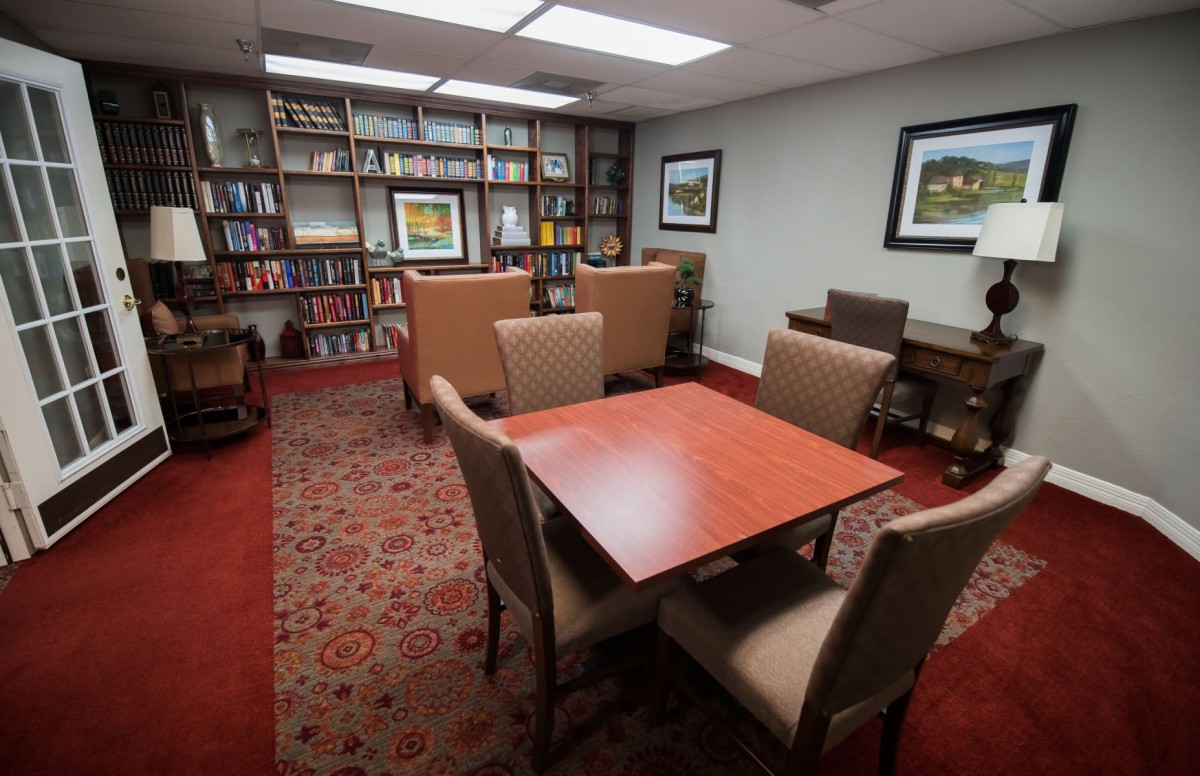 A cozy library reading room with bookshelves, a table, and chairs.
