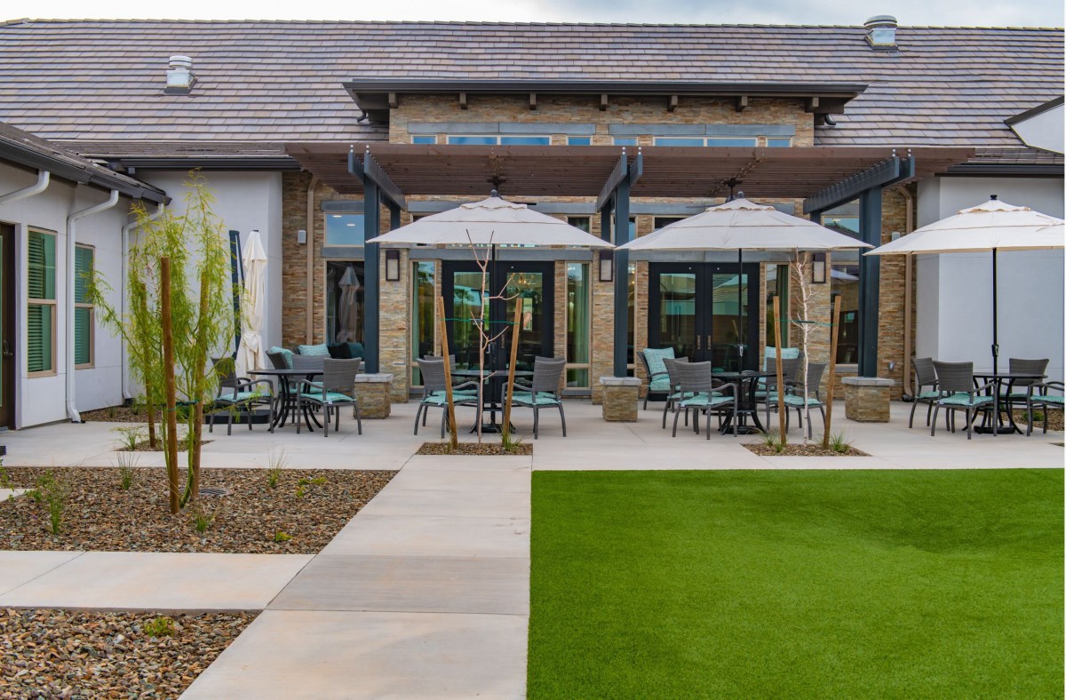 A modern patio with outdoor seating and umbrellas in front of a building.