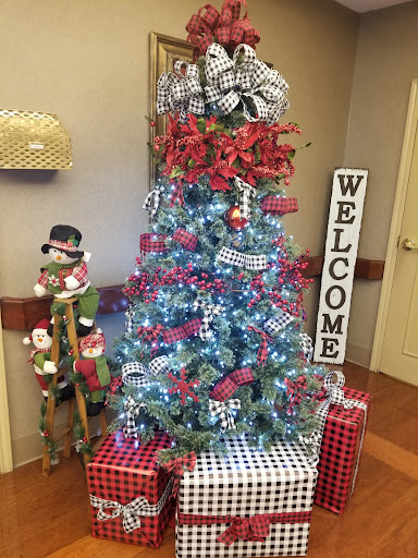 A beautifully decorated Christmas tree with presents and a cheerful welcome sign.