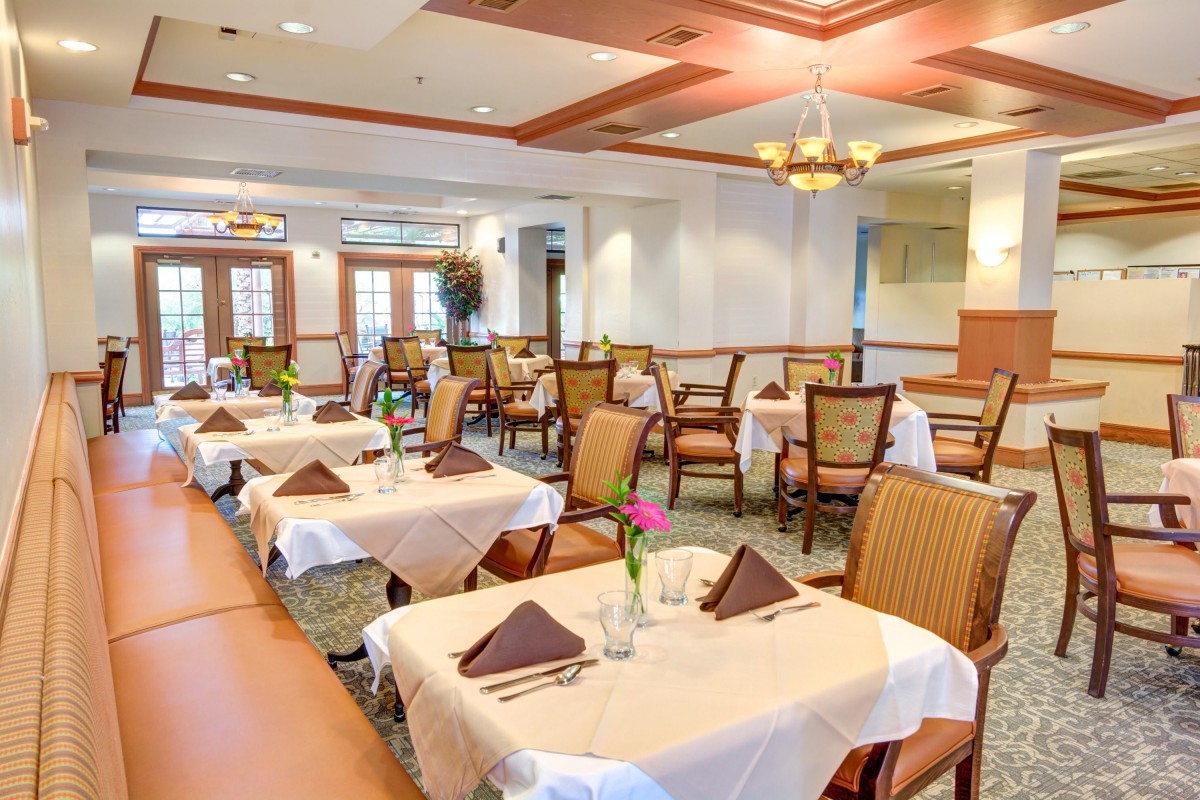 An elegant dining room with neatly arranged tables and chairs, featuring warm lighting and tasteful decor.
