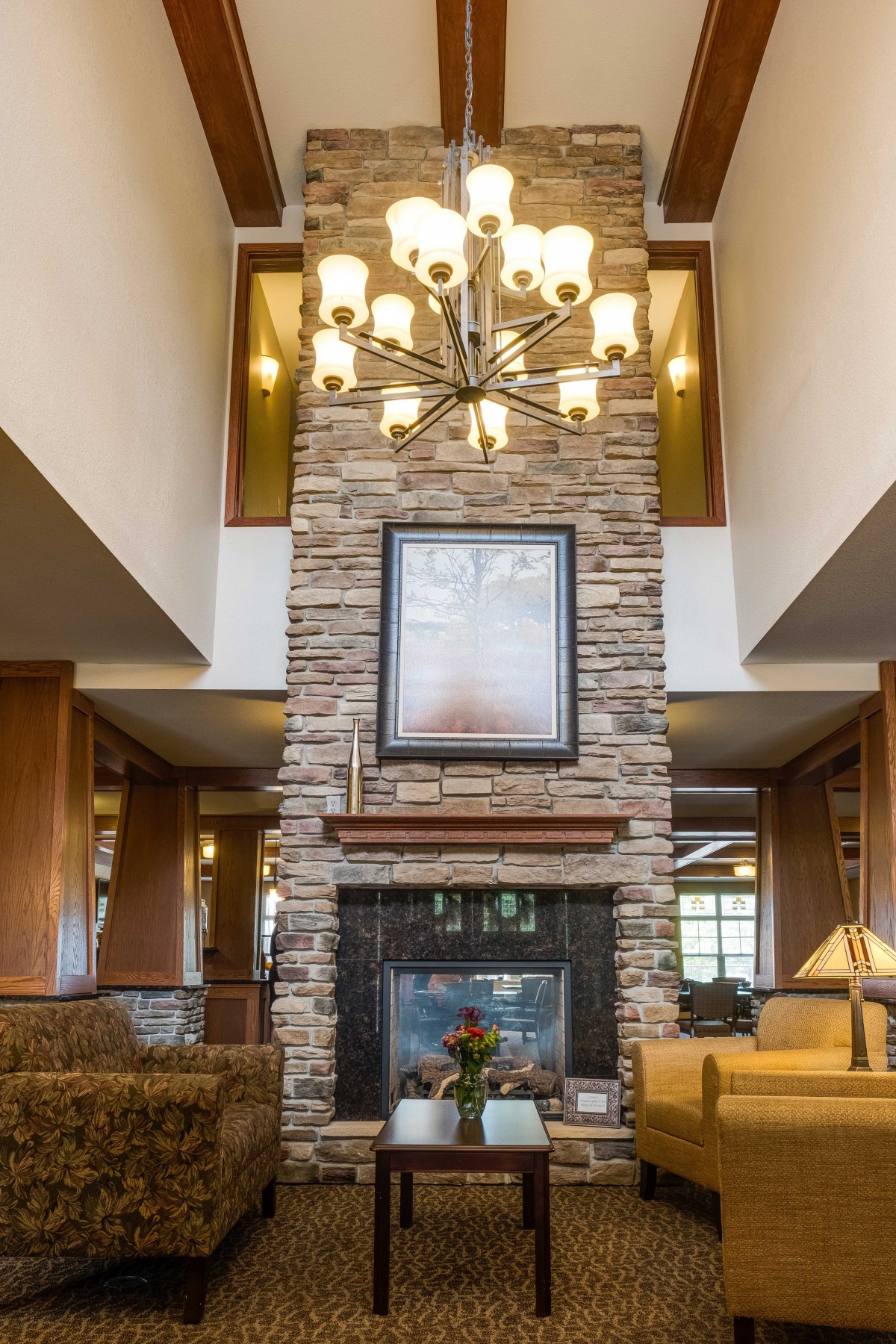 A cozy living room interior featuring a stone fireplace and an elegant chandelier.