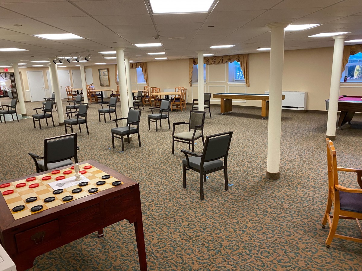 An empty indoor room with chairs arranged neatly and a game table in the foreground.