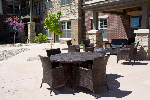 A modern outdoor furniture set featuring a round table surrounded by stylish chairs, set against a backdrop of stone buildings.