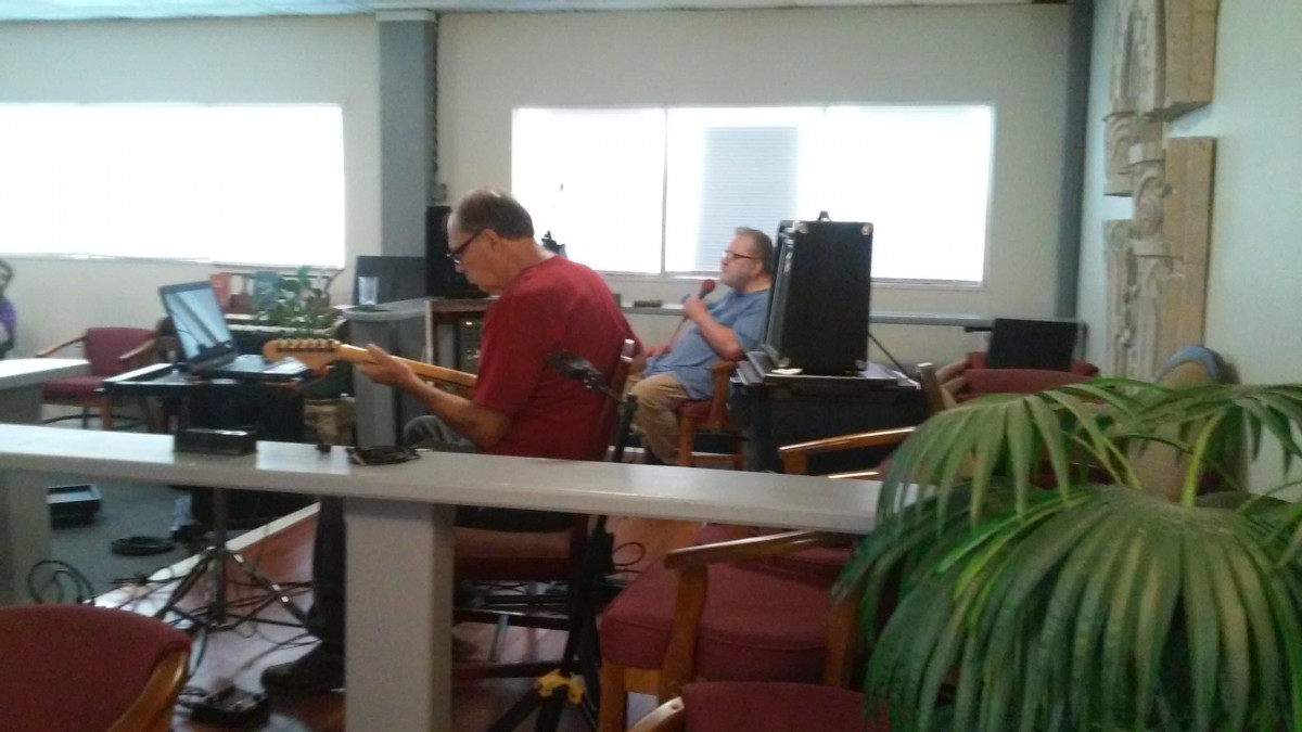 Musicians rehearsing indoors with a guitar and microphone setup.