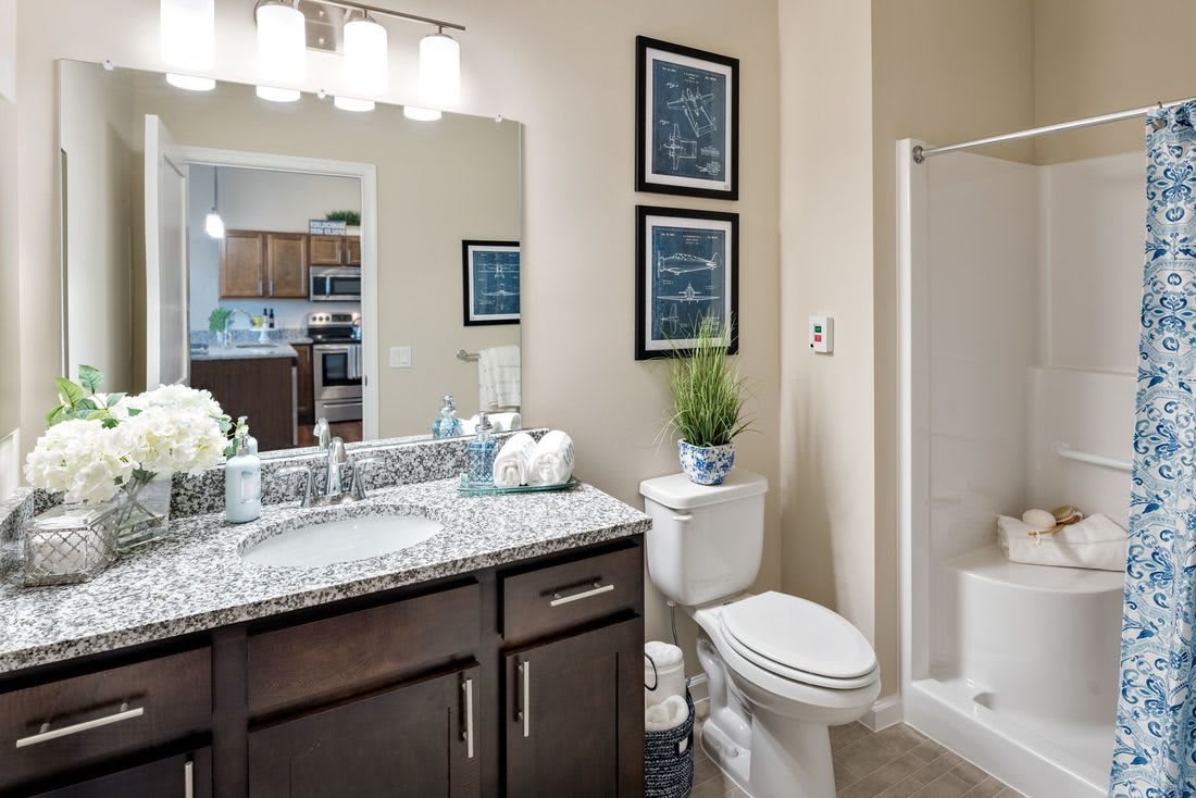 A modern bathroom interior featuring a sink with granite countertop, toilet, and shower.