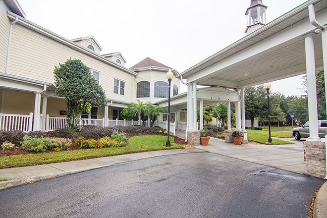 A beautifully landscaped entrance to a large building with a covered driveway.