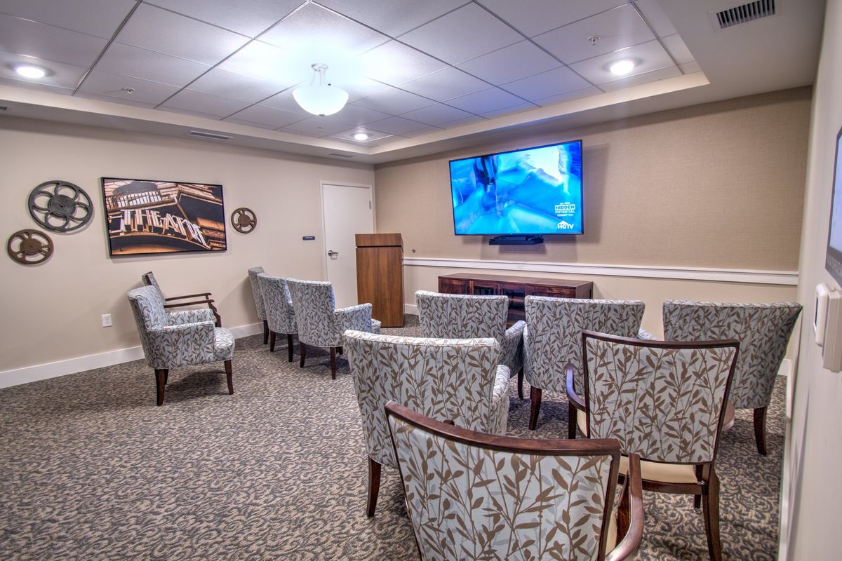 A small conference room with chairs arranged in rows facing a large television, suitable for presentations or meetings.