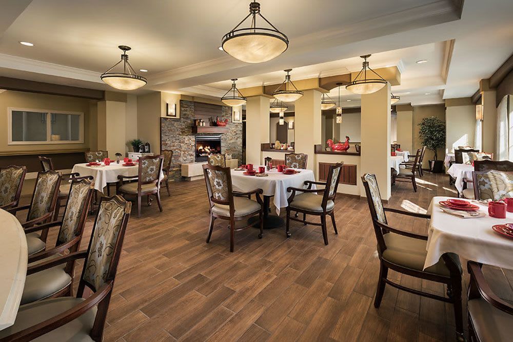 A well-decorated dining room with neatly arranged tables and chairs, featuring elegant lighting fixtures.