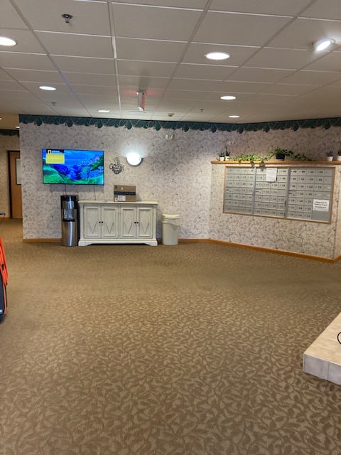 A spacious lobby area with a television, water cooler, and seating options.