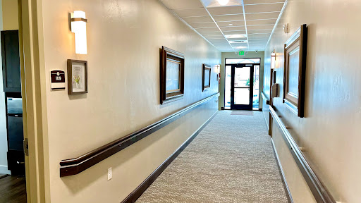 A well-lit hallway featuring framed artworks and a doorway leading outside.