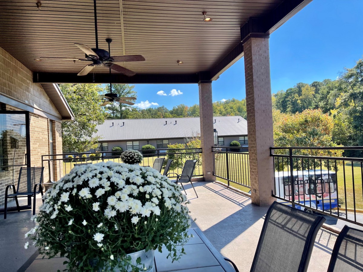A sunny day on a cozy patio with flowers, seating, and a scenic view.