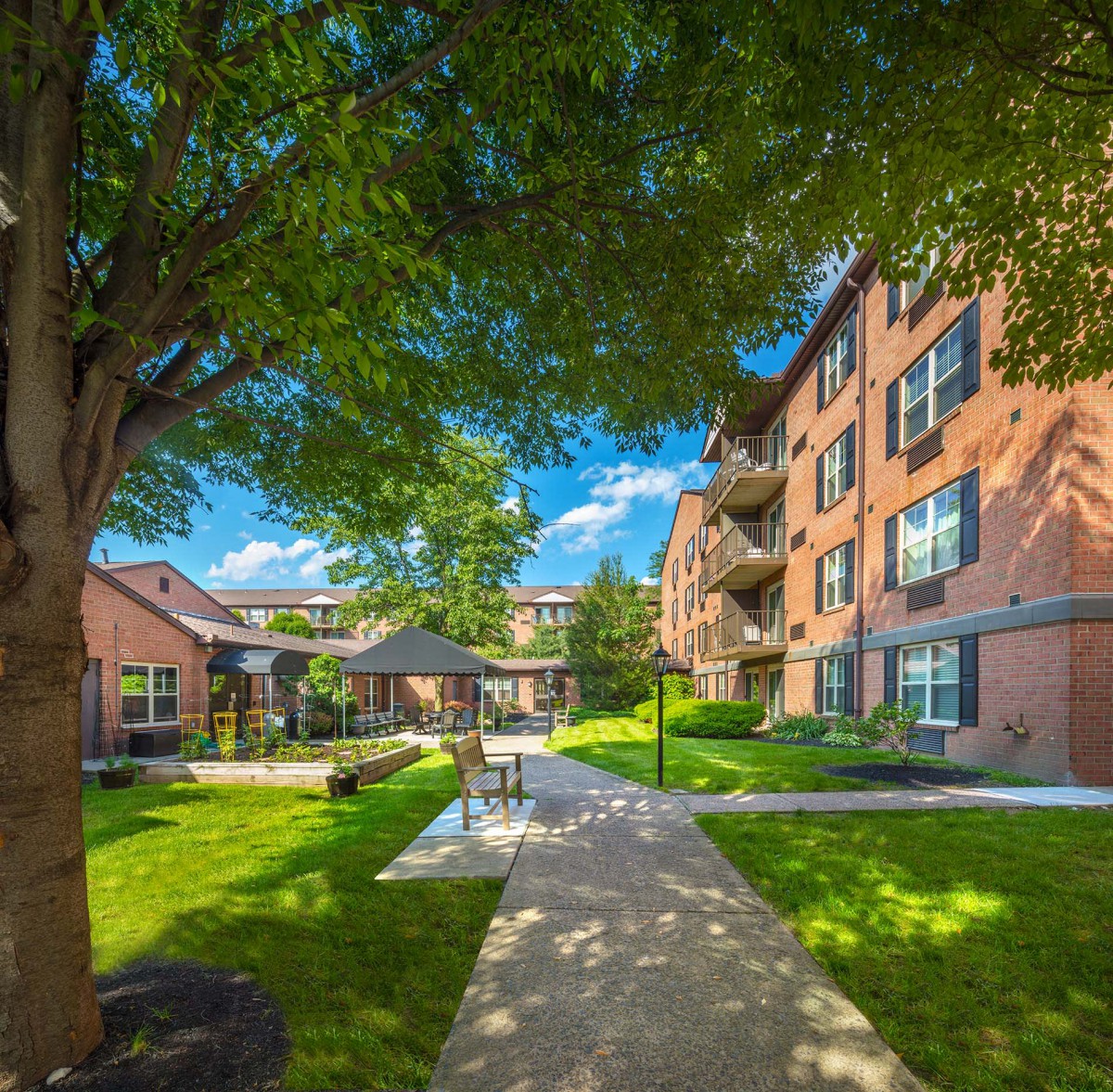 A well-maintained apartment complex with lush landscaping and a central walkway.
