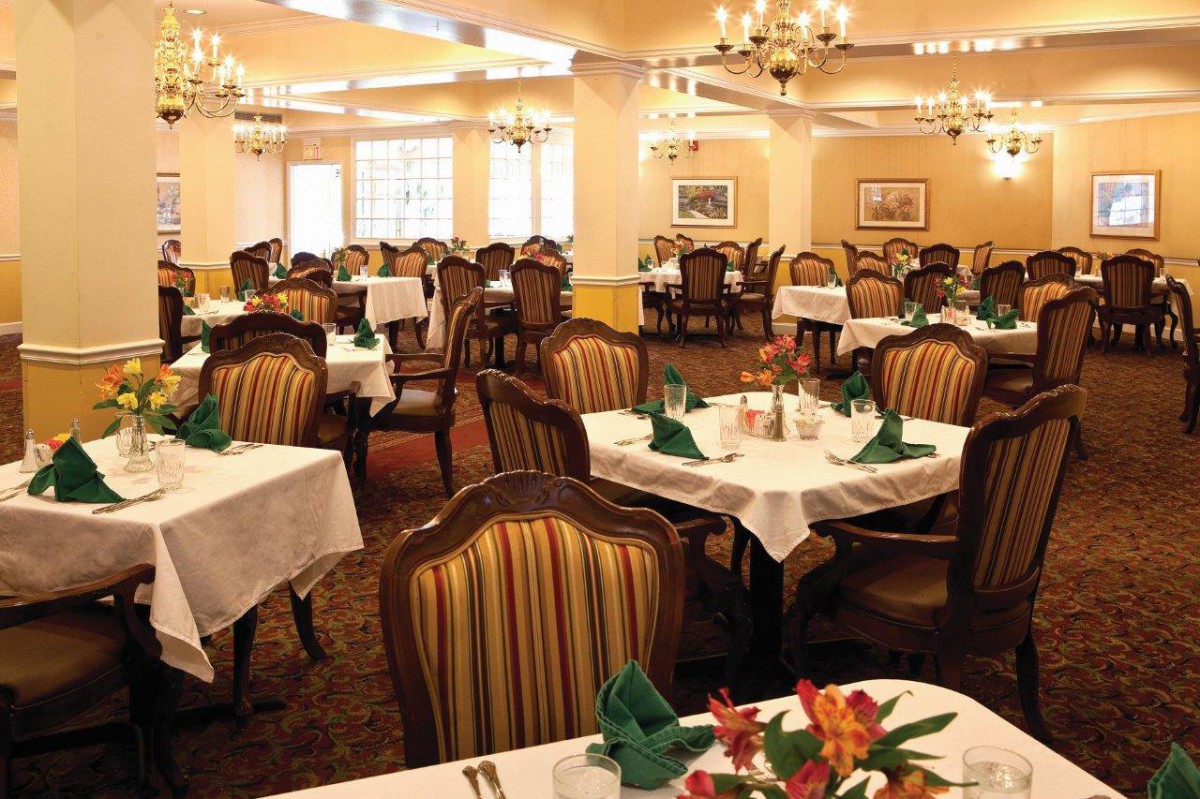 An elegant dining area with neatly arranged tables and chairs, featuring chandeliers and decor.