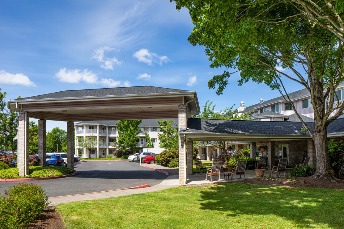 A hotel building with a covered entrance, surrounded by trees and a parking lot.