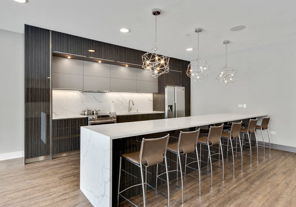 A sleek, modern kitchen featuring a spacious island with bar stools and elegant pendant lighting.