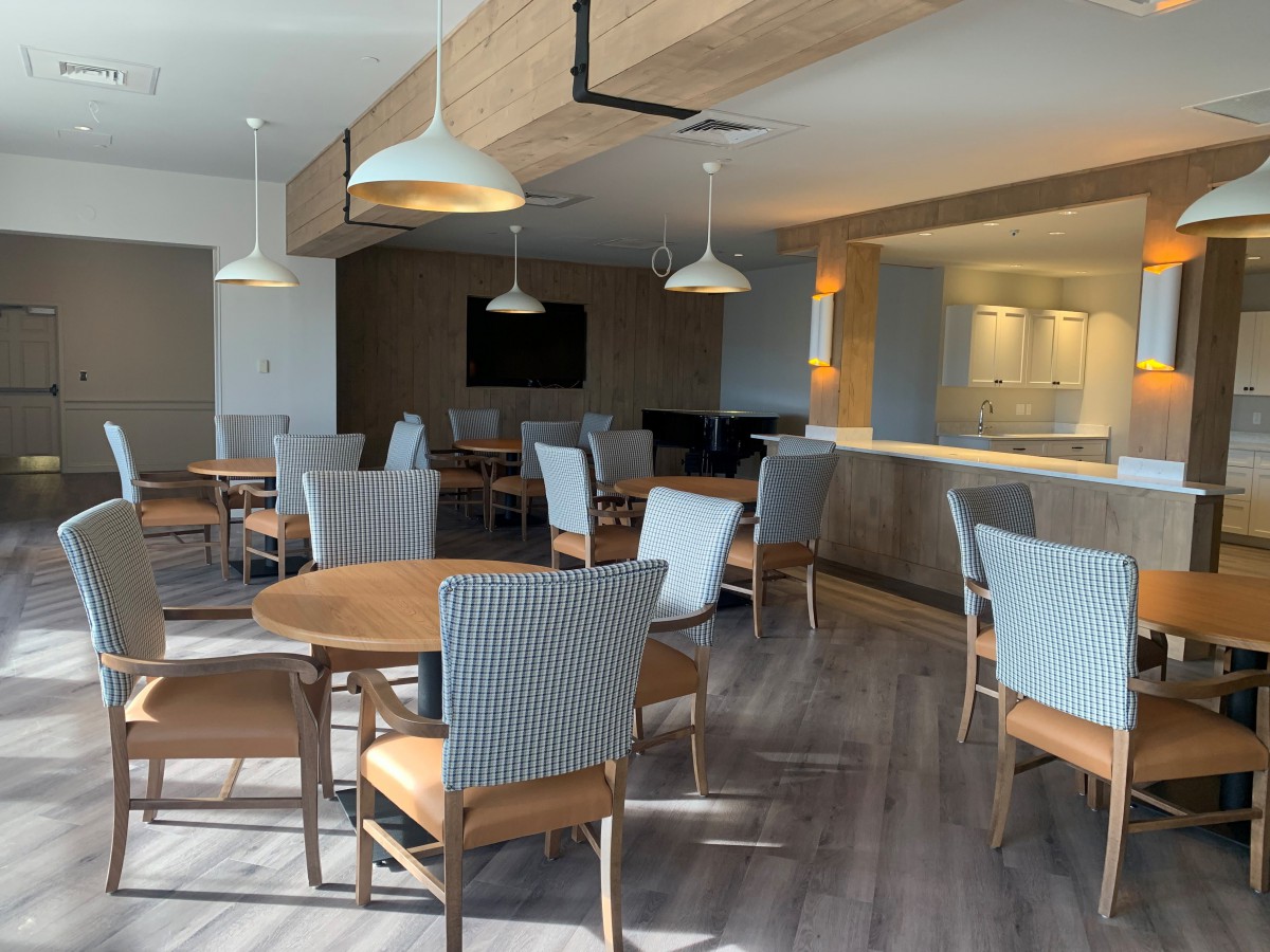 A modern restaurant interior with stylish tables and chairs under sleek lighting fixtures.