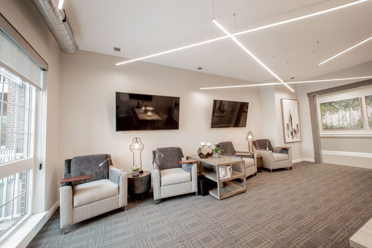 A modern waiting room with comfortable seating, sleek lighting, and mounted televisions.