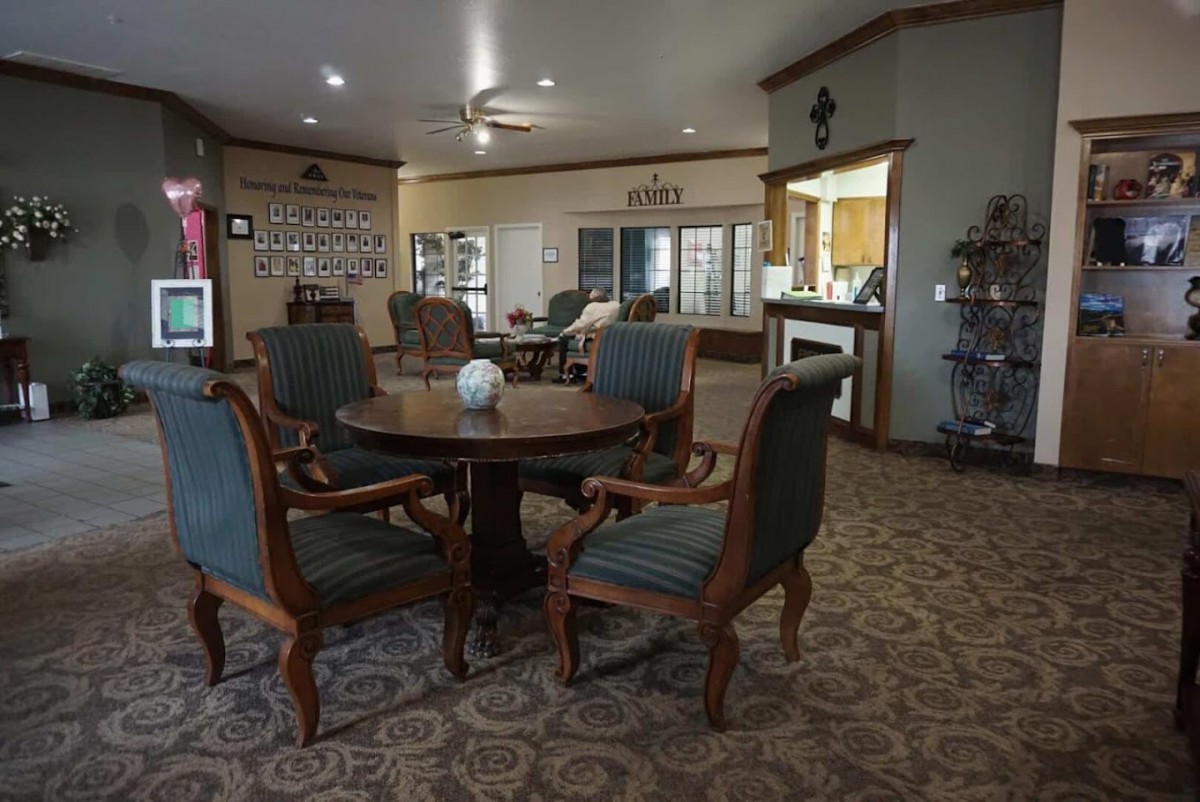A cozy living room with a table and chairs, warm lighting, and decorative elements.