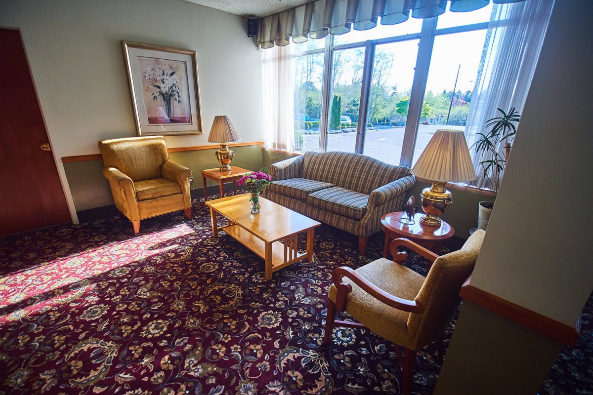 A cozy living room with a sofa, armchairs, a coffee table, and large windows letting in natural light.