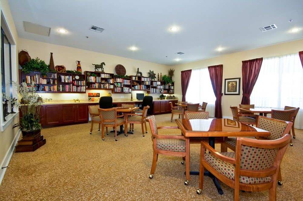 A spacious office or library area featuring tables, chairs, and bookshelves with various decor items.