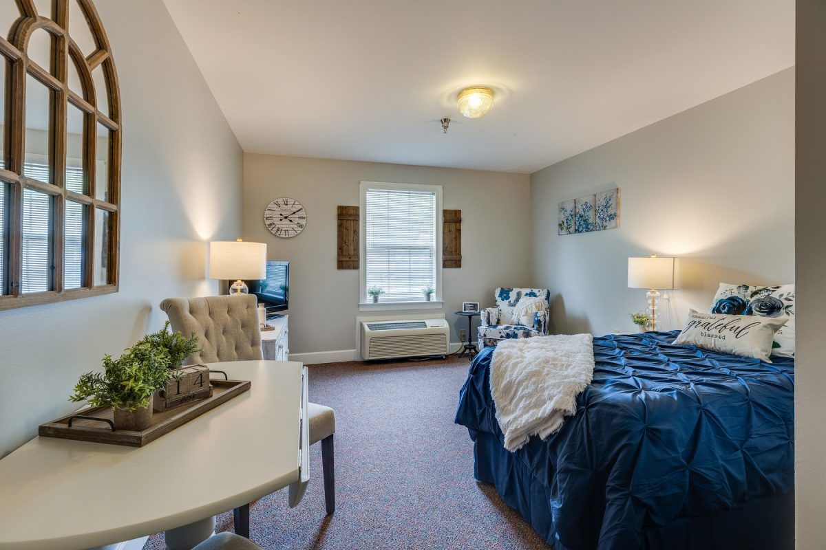 A cozy bedroom with a neatly made bed, two bedside lamps, and a window letting in natural light.