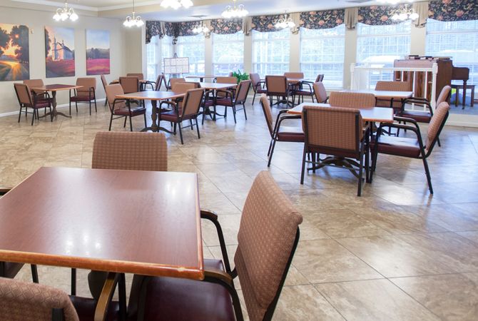 An empty dining area with neatly arranged tables and chairs, well-lit by large windows.