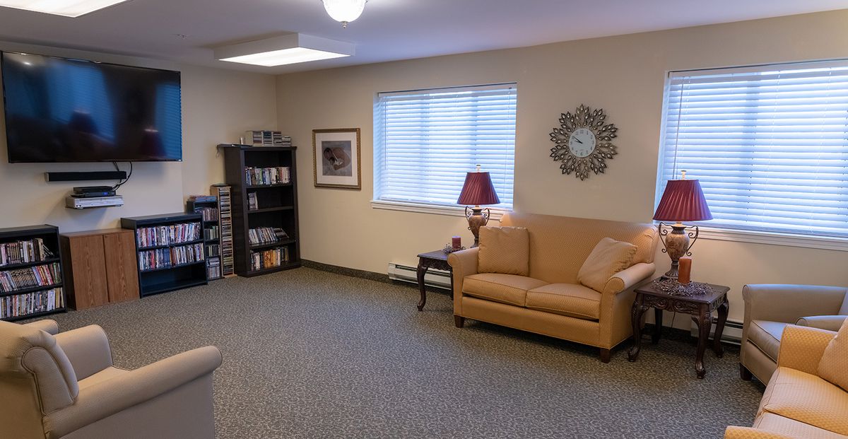 A cozy living room with a sofa, bookshelf, and lamp.