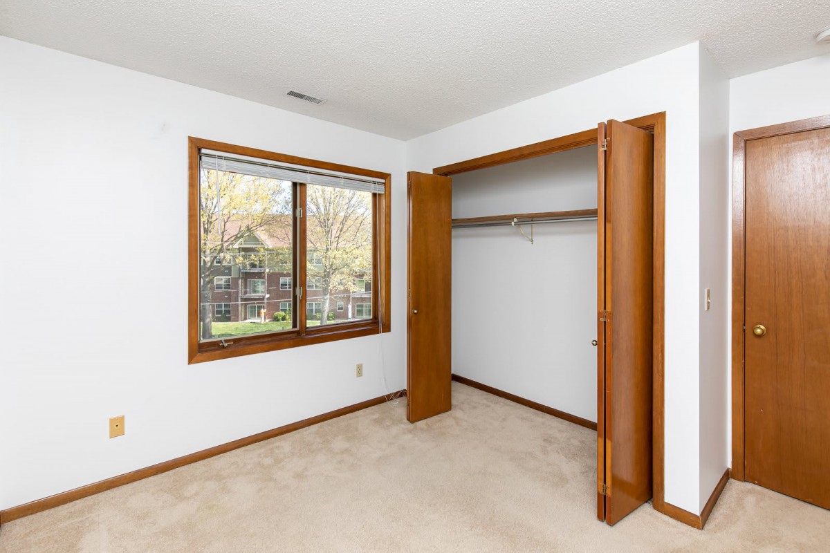 An empty room with a closet, window, and carpeted floor.
