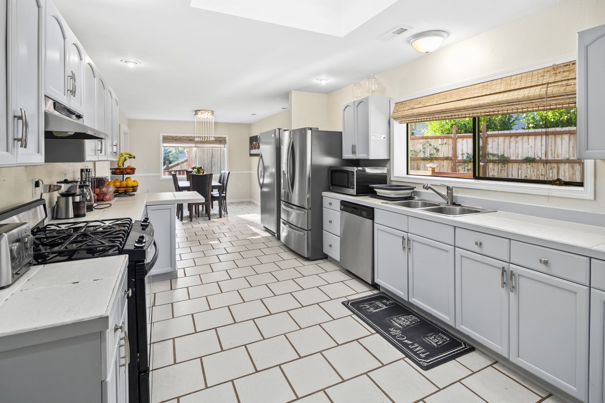 A spacious, modern kitchen with stainless steel appliances and white cabinetry, leading to a dining area.