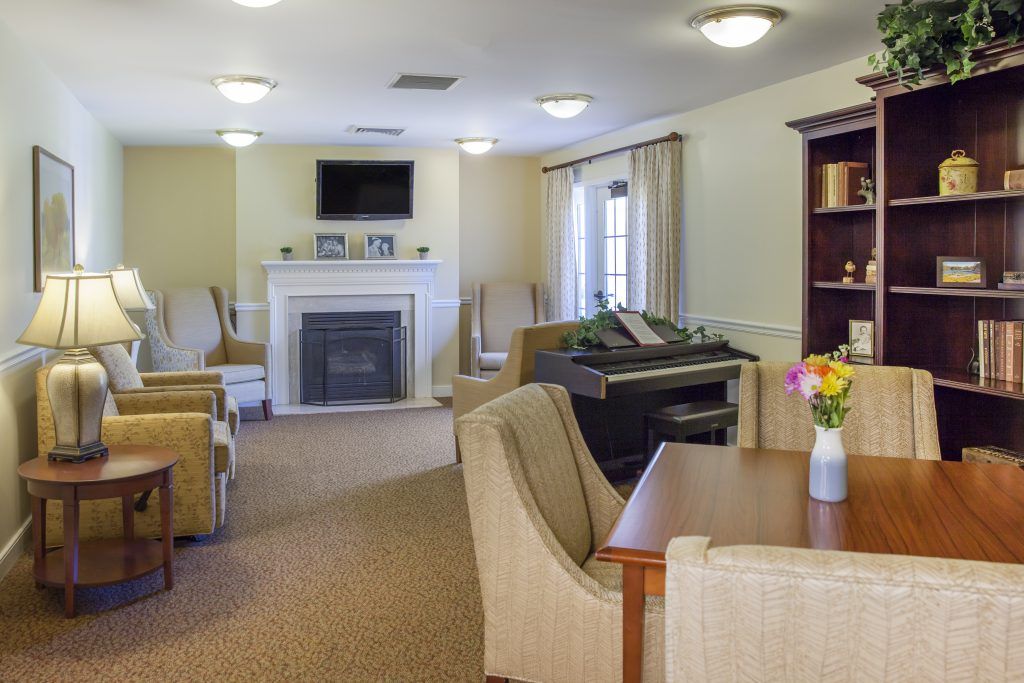 A cozy living room featuring a fireplace, television, piano, and comfortable seating.