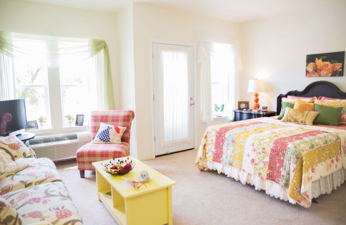 A bright and cozy bedroom with colorful decor and a comfortable seating area.