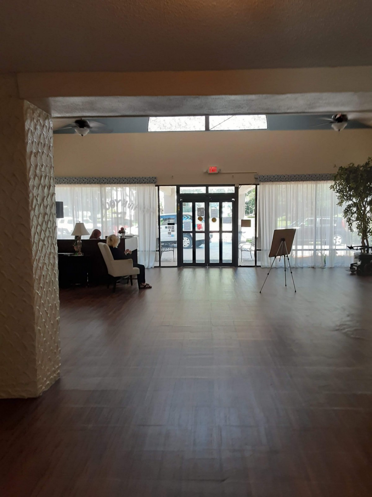 A spacious lobby with natural lighting, featuring a seating area and entrance doors.