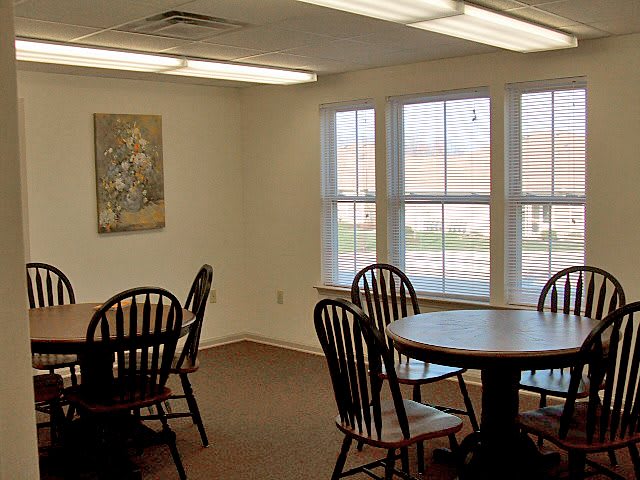 A dining area with multiple tables and chairs, well-lit by natural light from large windows.