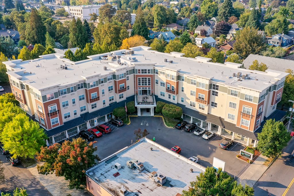 Aerial view of a residential building surrounded by trees and a parking lot.
