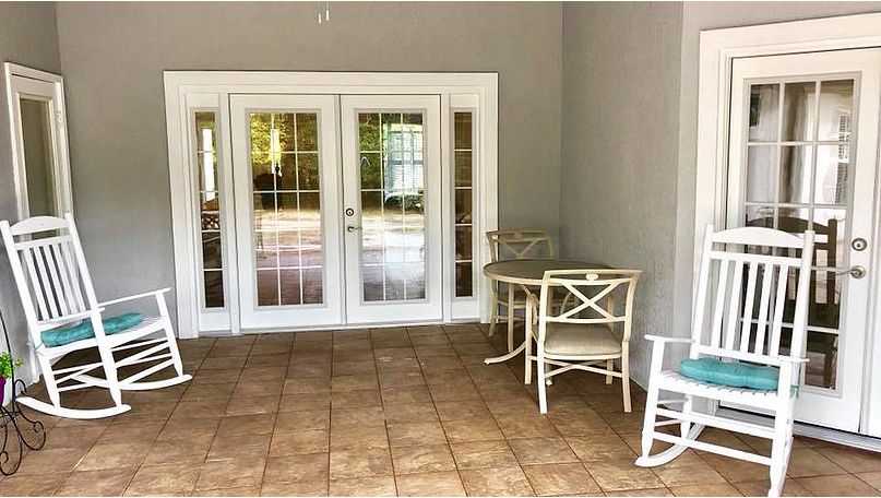 A cozy patio area with a table and two chairs, featuring tiled flooring and glass doors leading inside.