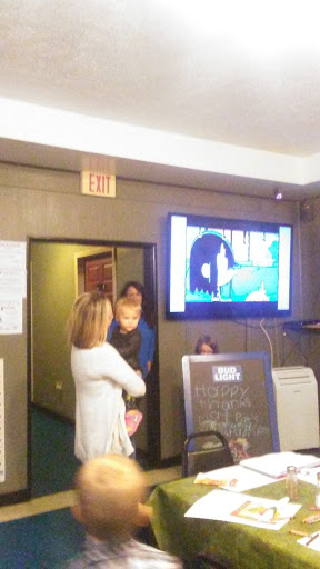 An event setting with people gathered around a screen displaying artwork.